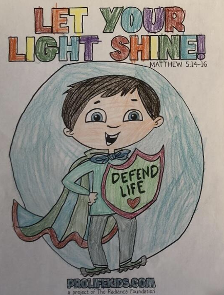 Colorful hand-drawn poster with the words "LET YOUR LIGHT SHINE!" at the top and a cartoon boy wearing a cape holding a shield that says "DEFEND LIFE". The background is light blue with a rainbow-colored text and a small Bible reference, Matthew 5:14-16.