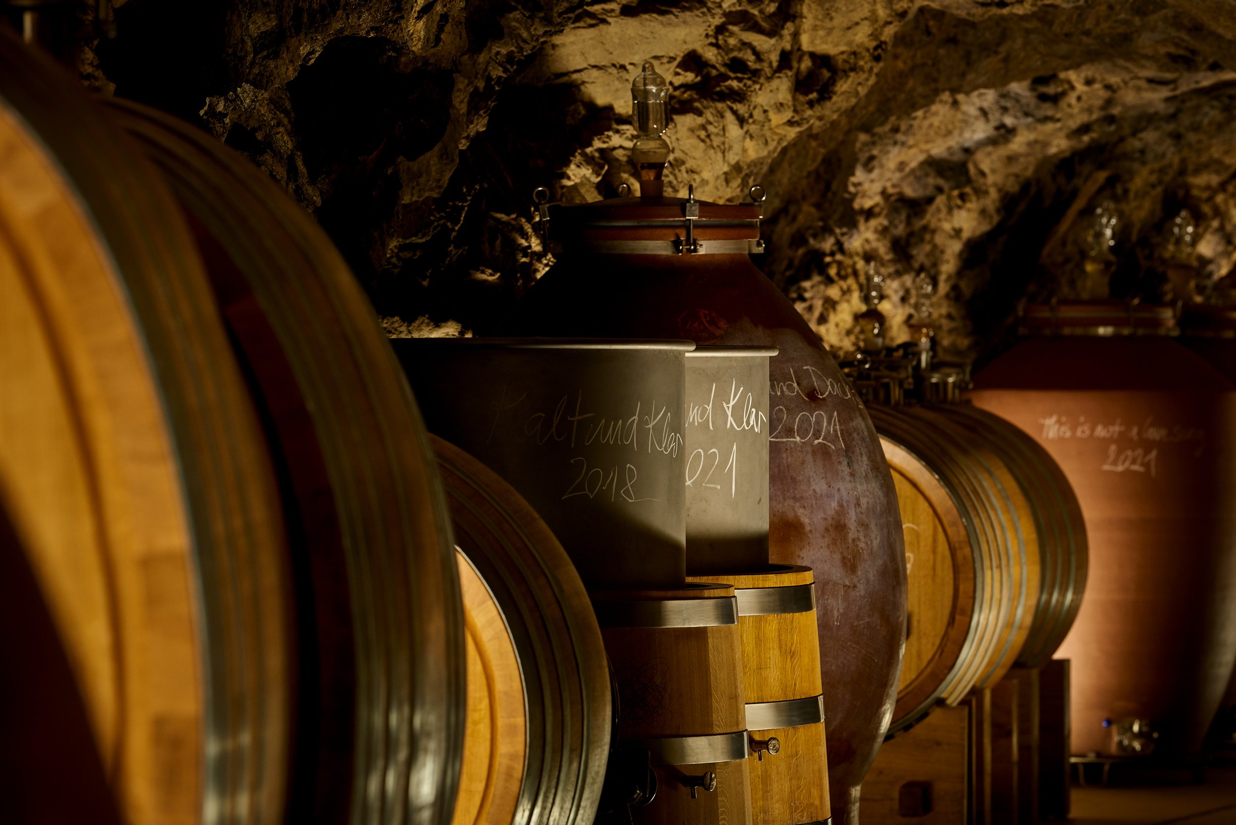 Große Weinfässer in einer Weinkellerei, die in einem Keller aus Stein lagern