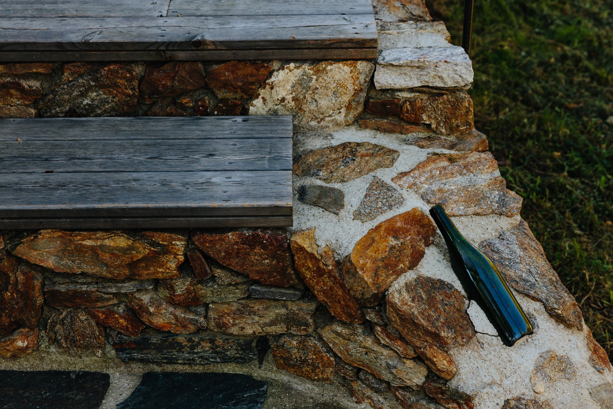 Ein Gemäuer aus Steinen und Holz mit einer leeren grünen Flasche liegt auf einer Steinmauer.