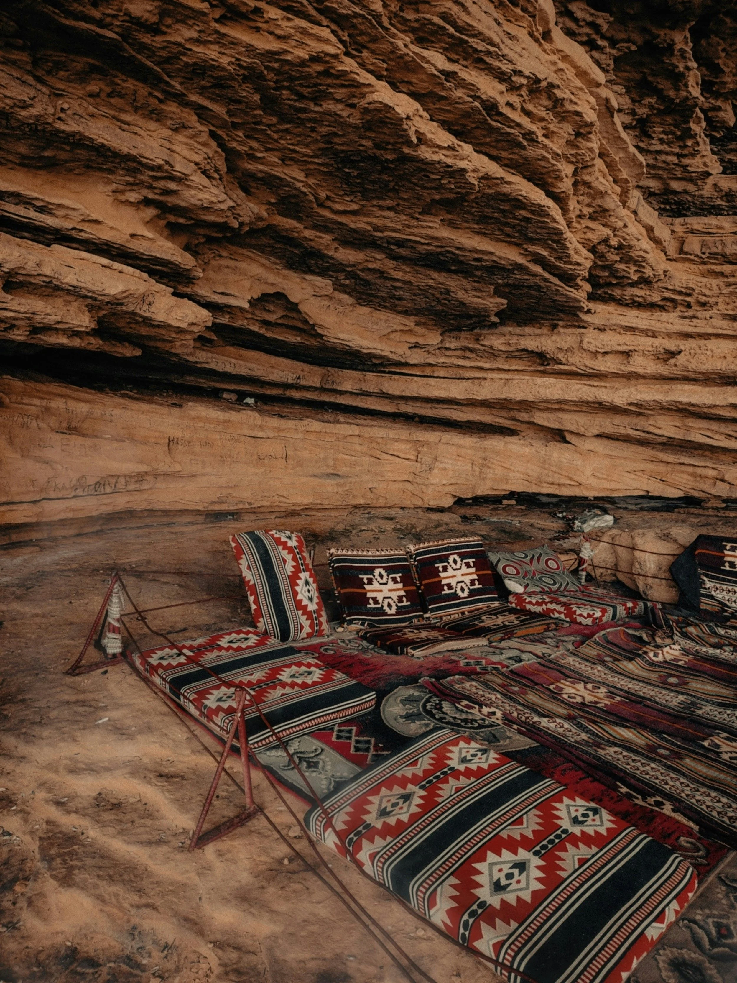Arab floor seating area with patterned blankets and pillows between walls of a mountain.