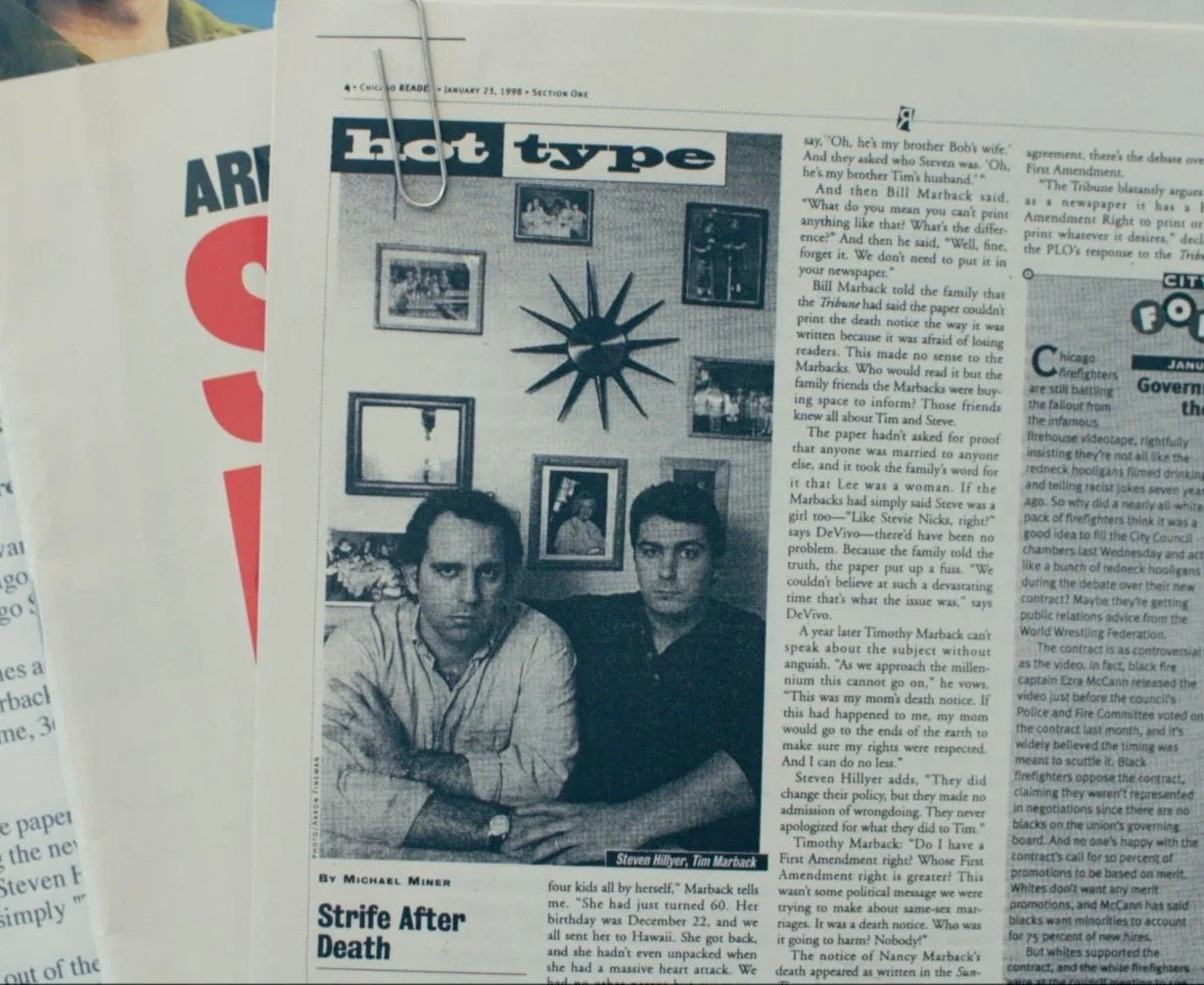 Black and white newspaper article titled 'Hot type' featuring a photo of two men sitting on a couch, with a wall decorated with picture frames and a sunburst mirror behind them. The caption identifies the men as Steven Hillyer and Tim Marback.