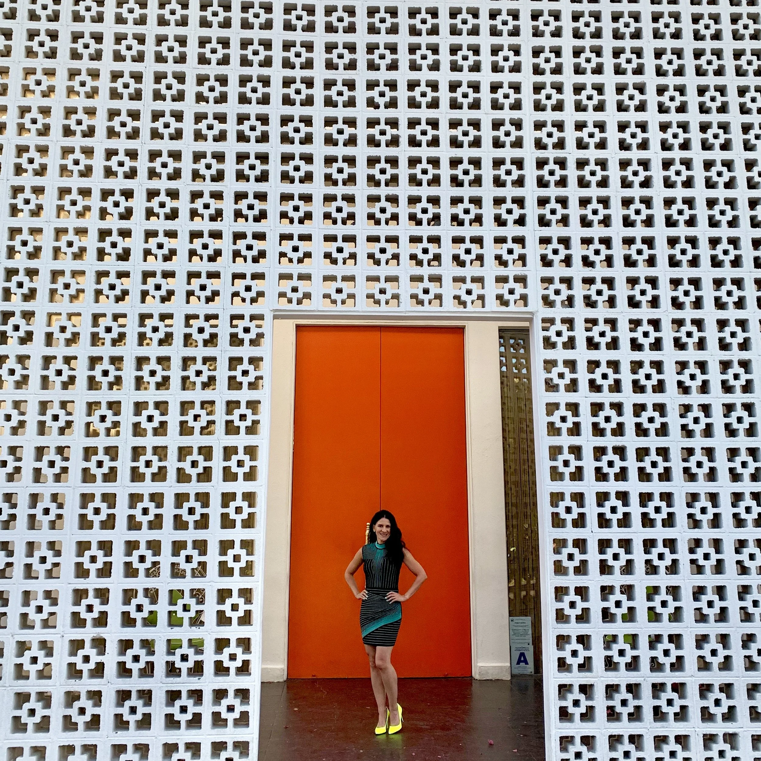 Jennifer wearing neon colors and standing in front of the orange door at The Parker in Palm Springs, California