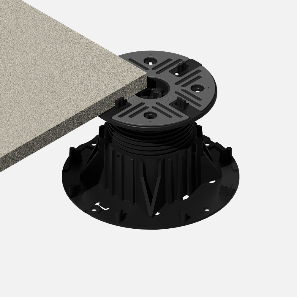 Close-up of a furniture adjustable foot, with a black plastic base, threaded stem, and a circular base plate, supporting a grey textured tabletop.