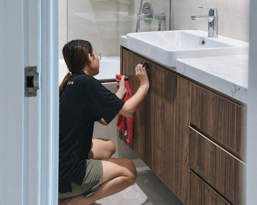 J+U cleaner wiping a bathroom cabinet