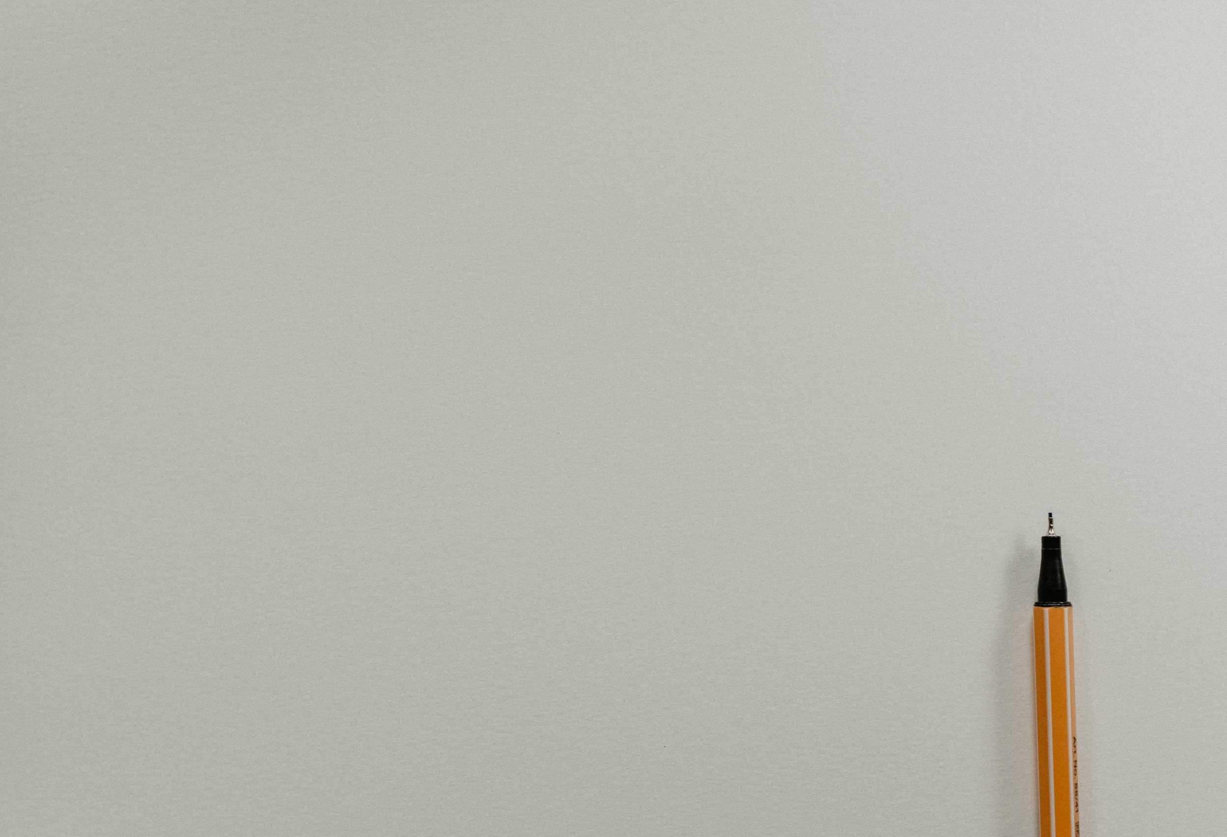 A yellow and black marker pen lying on a plain light grey surface.