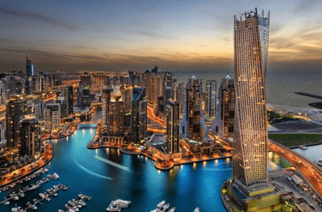 Aerial view of a city skyline at dusk, featuring illuminated skyscrapers, a winding canal, luxury yachts, and a prominent twisted skyscraper on the right.