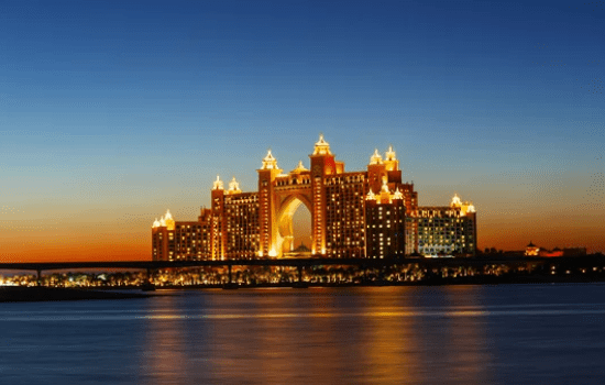 Illuminated luxury hotel at sunset with ocean in foreground