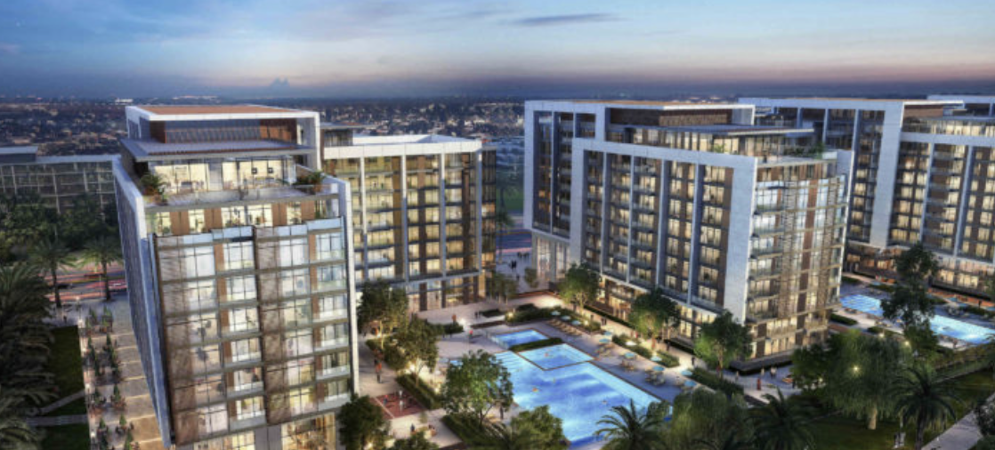 Modern residential buildings with large windows surrounding a central courtyard featuring a swimming pool and landscaped gardens, under a twilight sky.