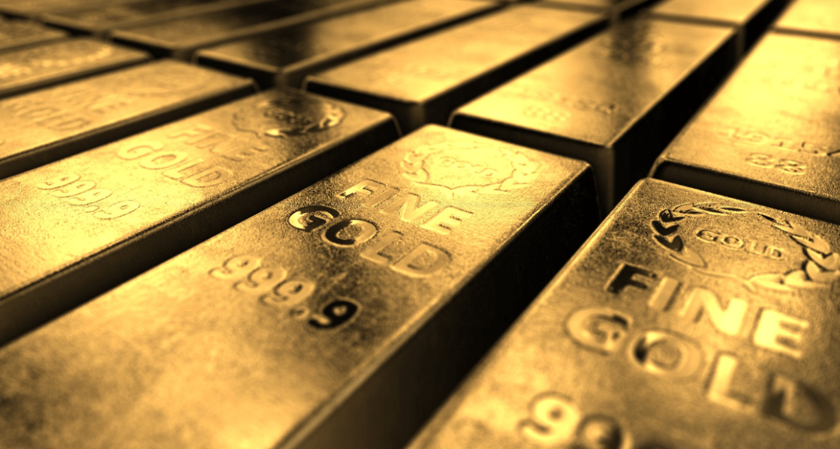Gold bars with inscriptions 'FINE GOLD' and '999.9' stacked closely.