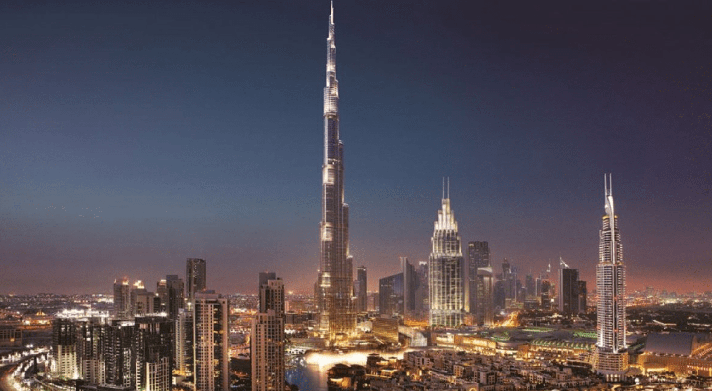Downtown Dubai skyline at night, featuring illuminated skyscrapers and the Burj Khalifa.