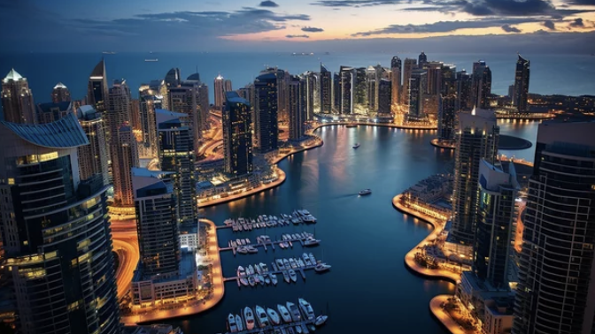 Aerial view of a modern city skyline with high-rise buildings and a marina filled with yachts at night, illuminated by city lights.