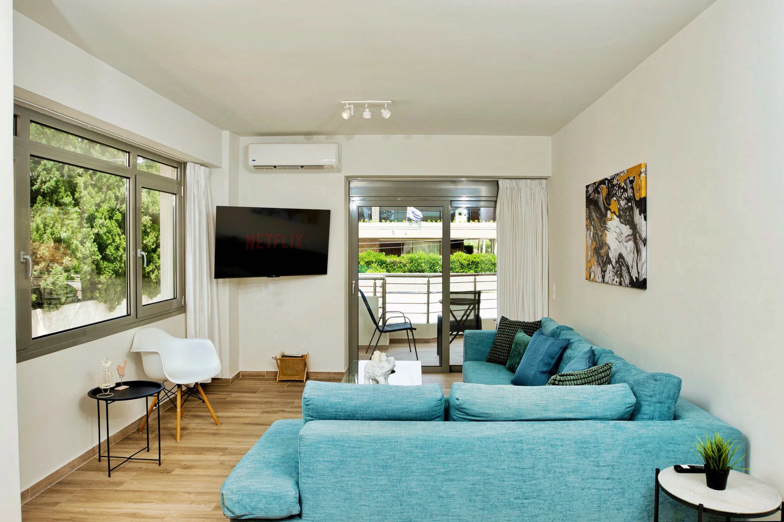 Bright living room opening to balcony with greenery