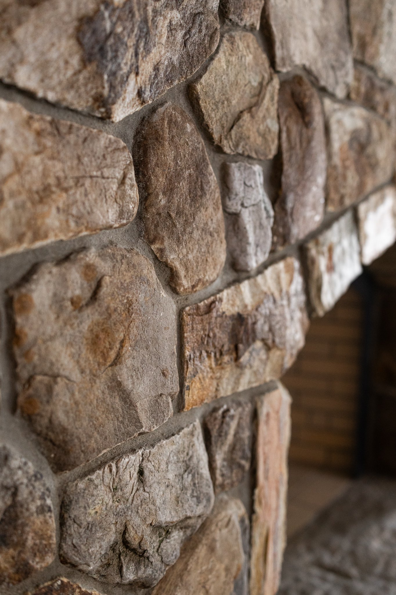 Close-up of a stone brick wall showing various sized and colored stones with mortar in between.