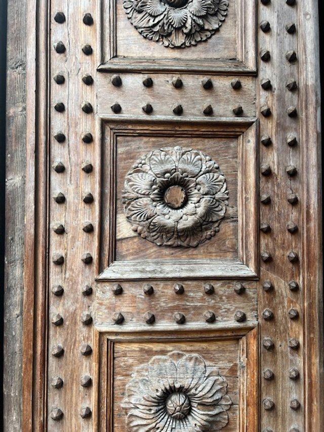 Ornate wooden door with floral carvings and decorative studs.