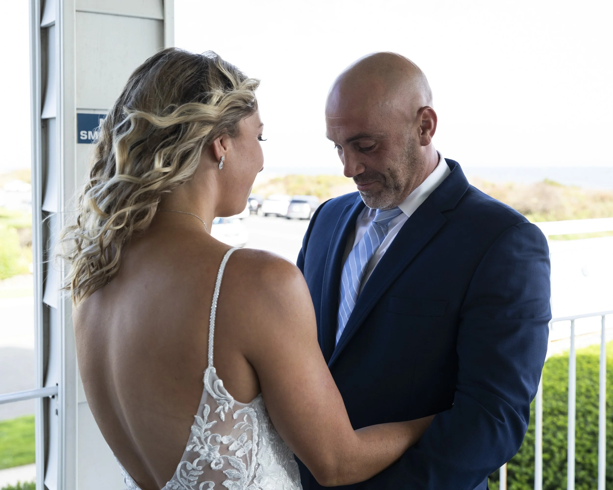 A bride and groom share a tender moment on their wedding day, holding hands and looking at each other with love.
