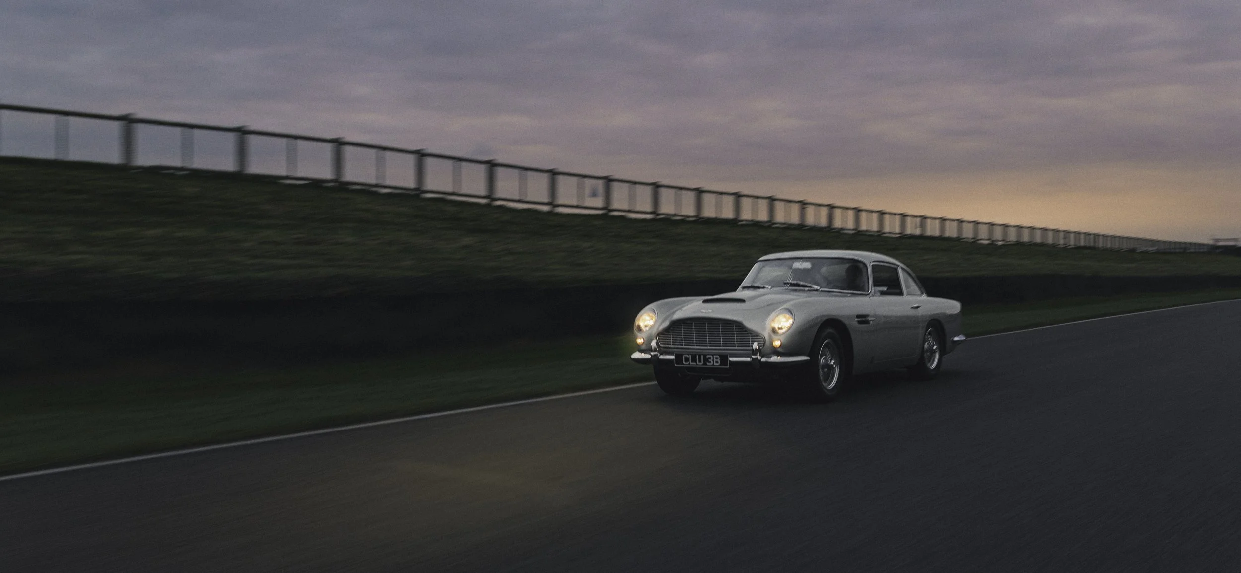 vintage car Aston Martin racing on motor circuit blue hour 