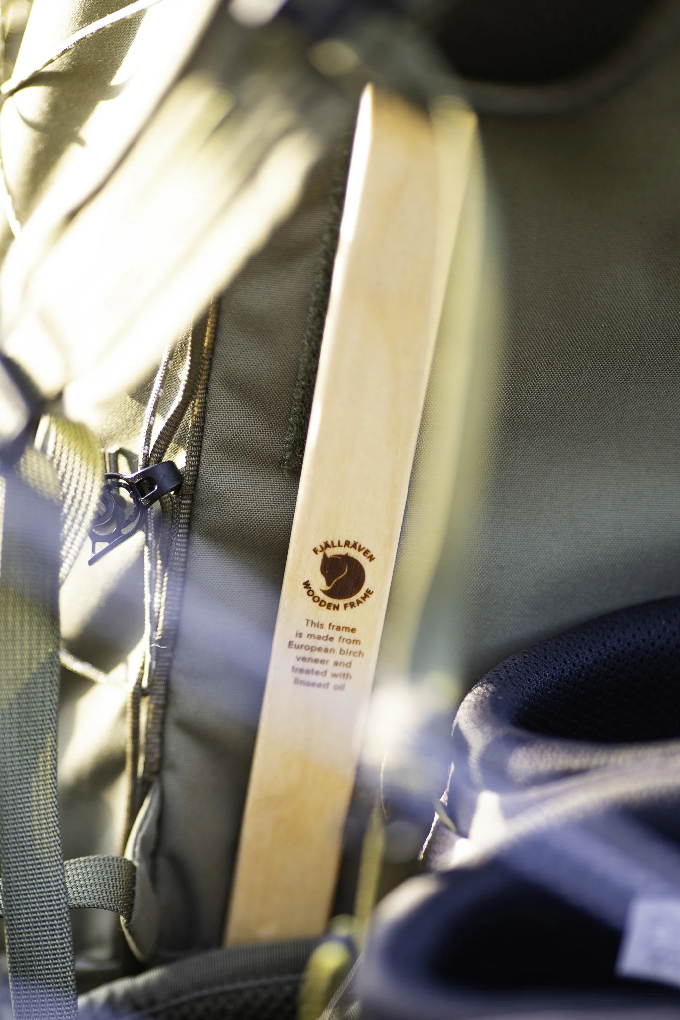 Close-up of a wooden frame with a circular logo and text, placed inside a backpack.
