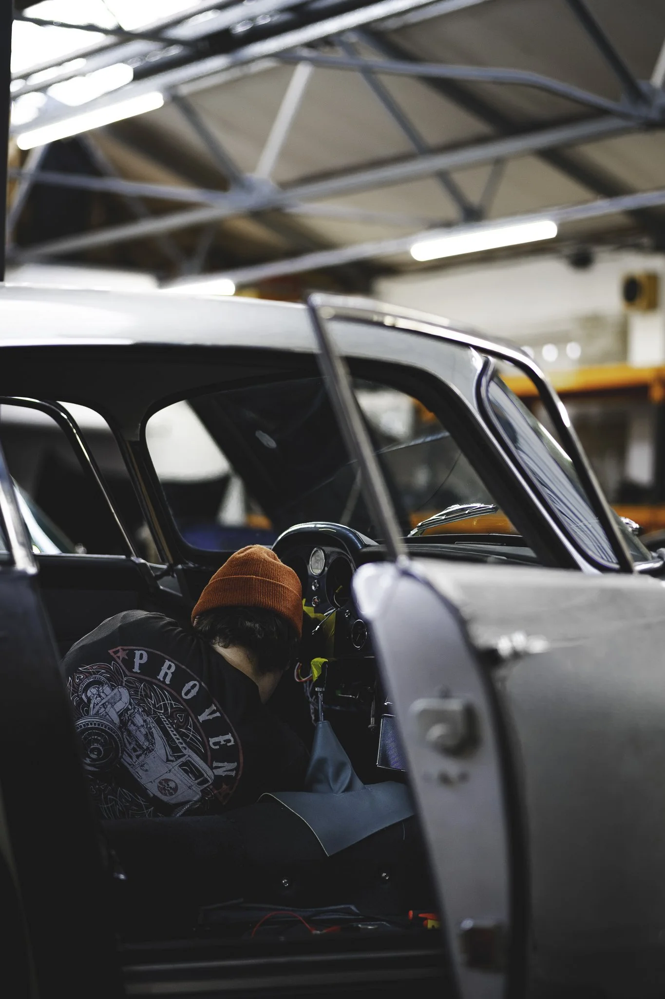 A person wearing a red hat working on a vintage race car in a garage
