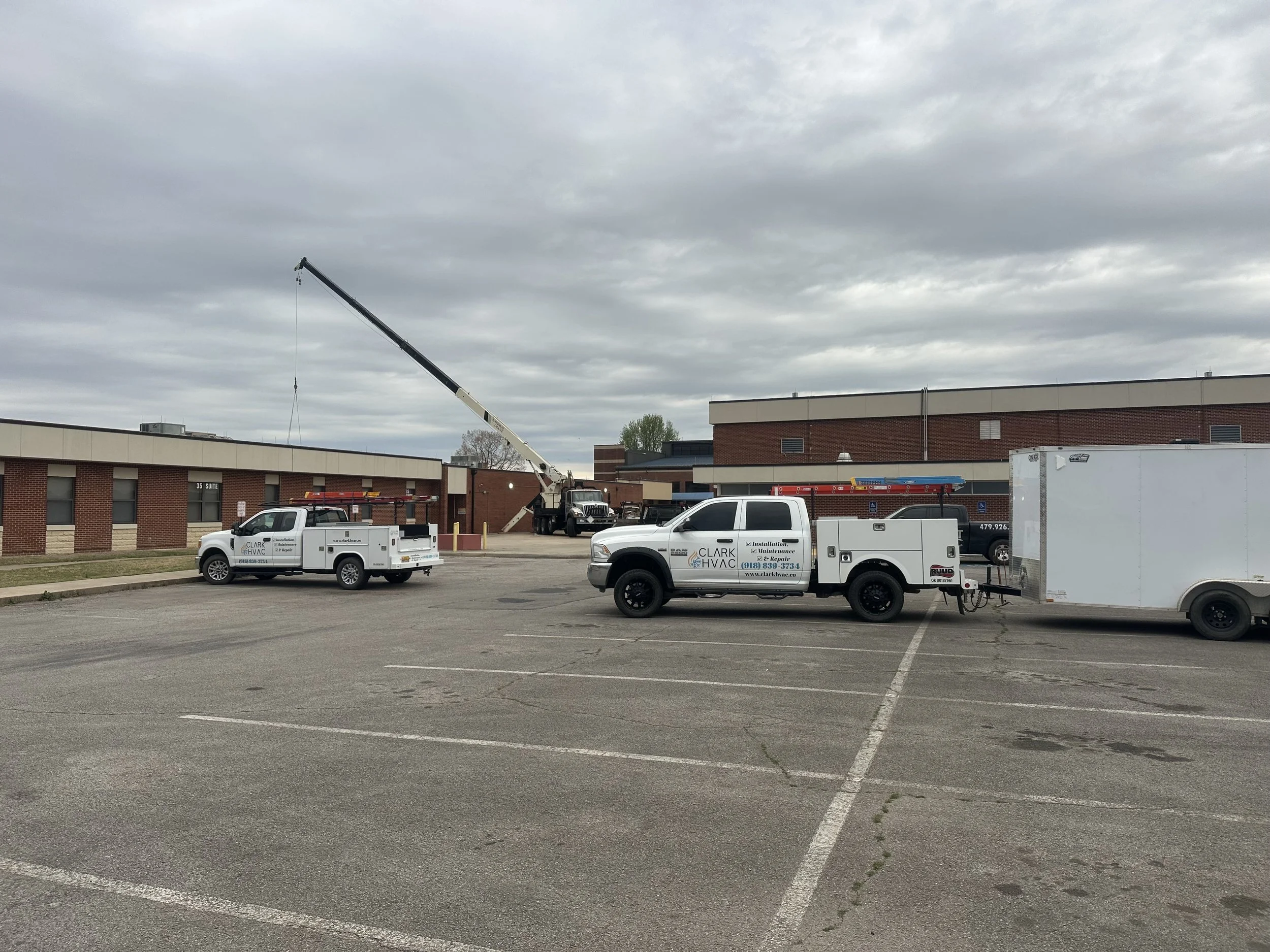 Clark HVAC commercial rooftop unit being lifted by crane at a school building