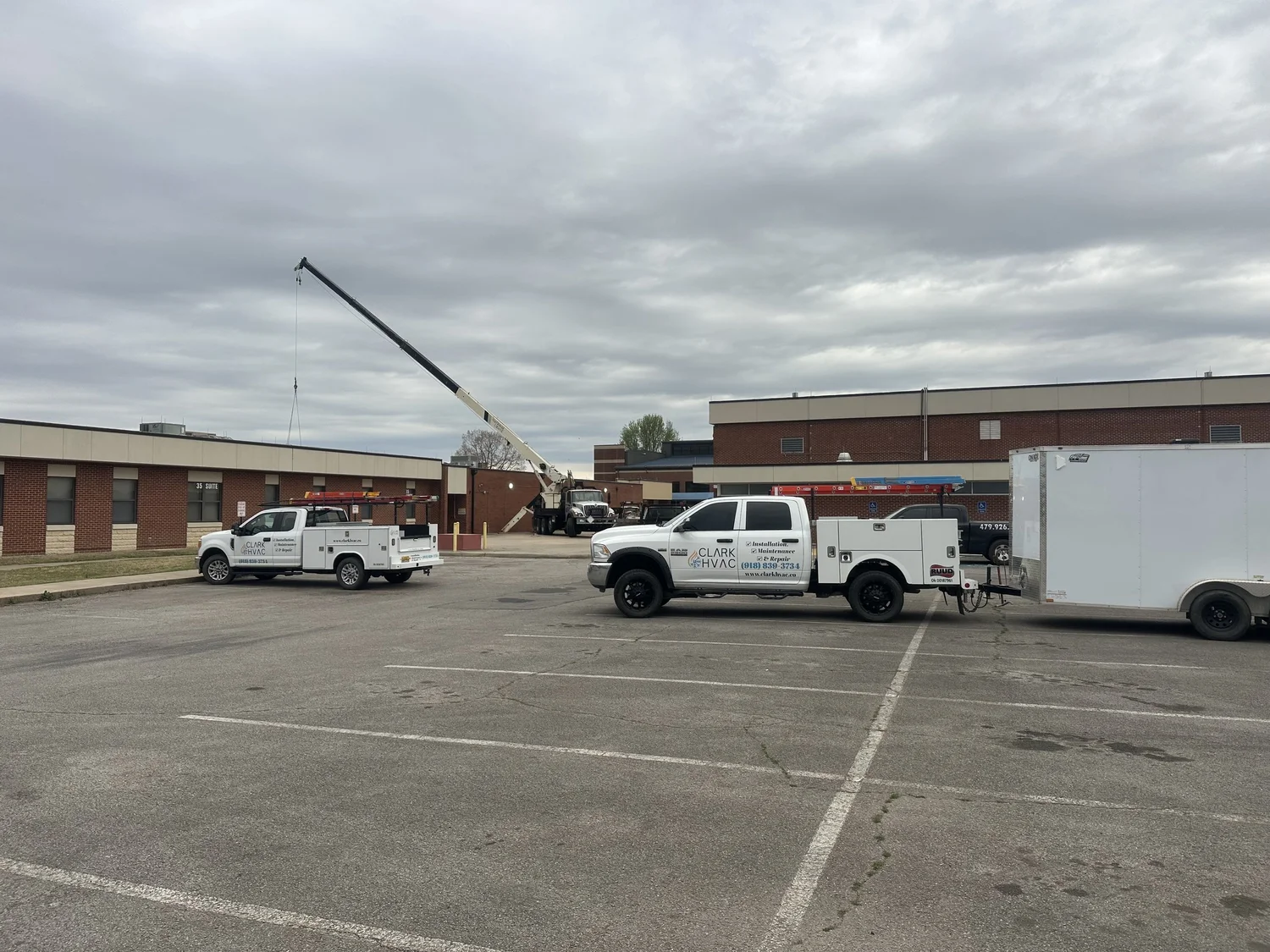 Crane setting a commercial rooftop HVAC unit on a school building for Clark HVAC