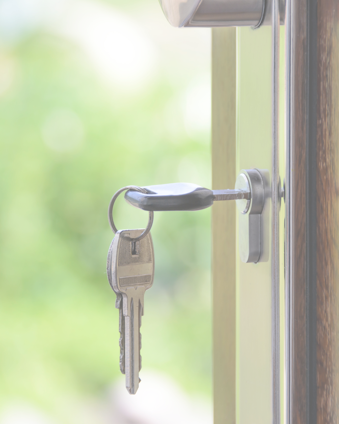 A key inserted into a door lock with a blurred green exterior background.