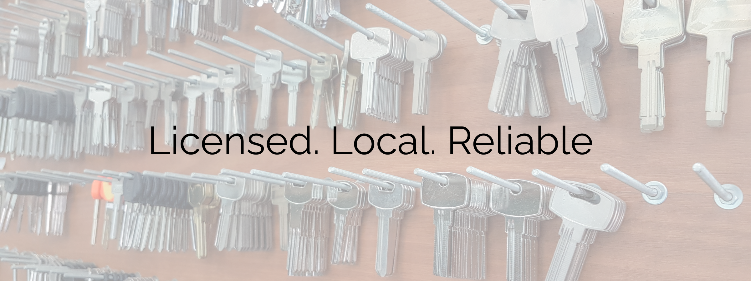 A wall display of numerous metal keys organized on hooks, with the words 'Licensed. Local. Reliable.' overlaid in black text.