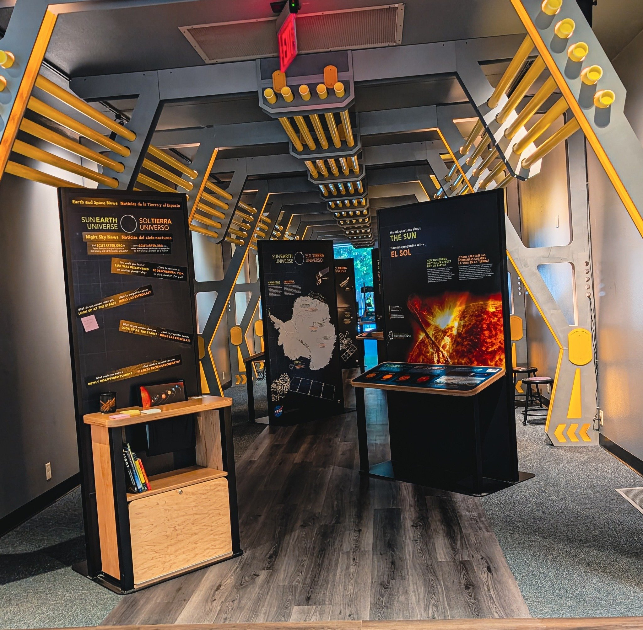 Exhibit area with informational panels about the sun, space, and earth, featuring diagrams, text, and a fiery sun graphic, inside a modern museum with yellow structural accents.