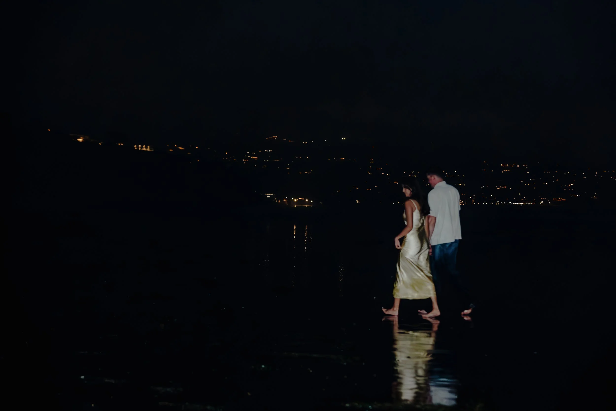 A couple walking barefoot on Black's beach in San Diego at night during engagement photoshoot