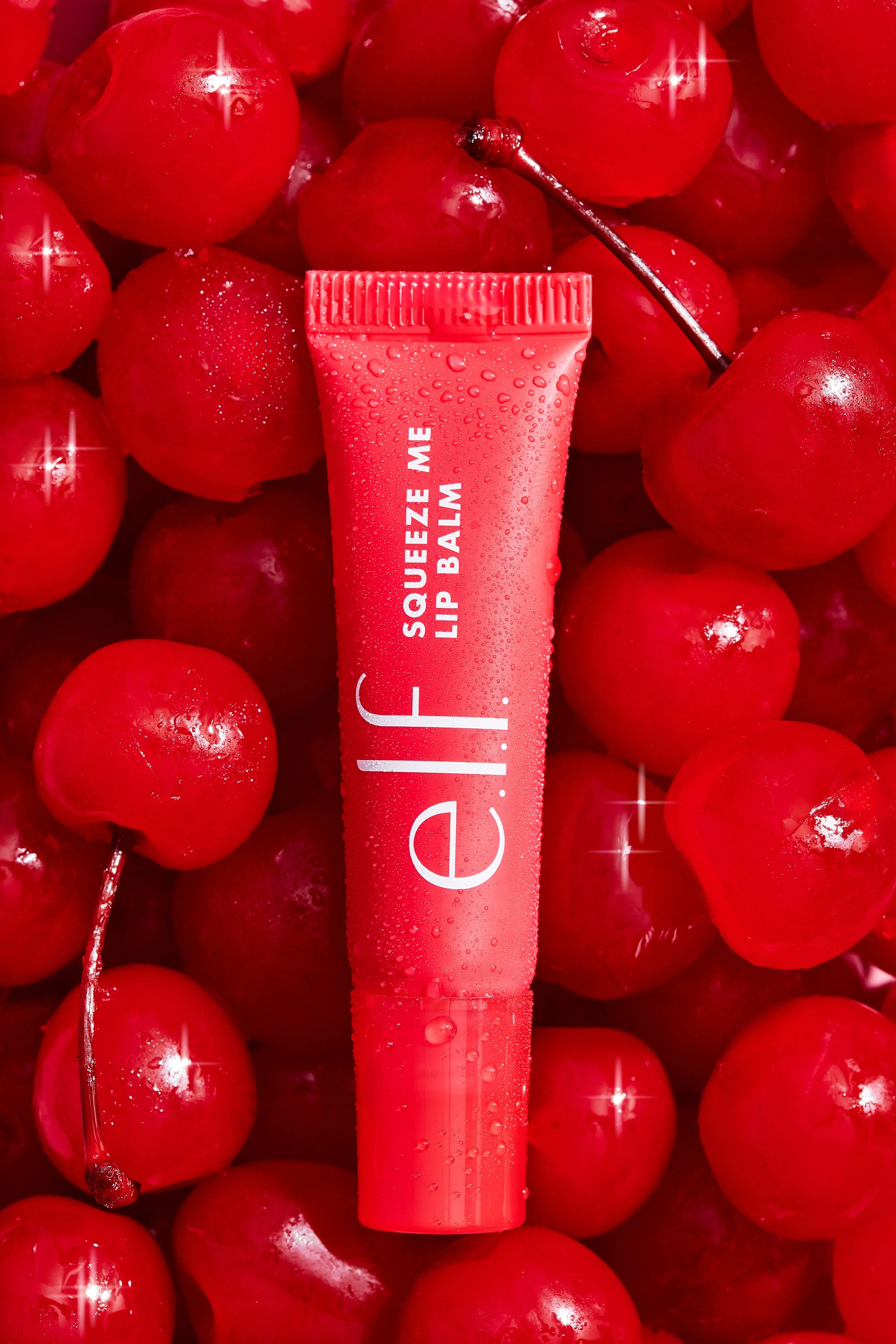 A pink squeeze tube of Lip Balm lying on red cherries, with some cherries having visible stems and water droplets.