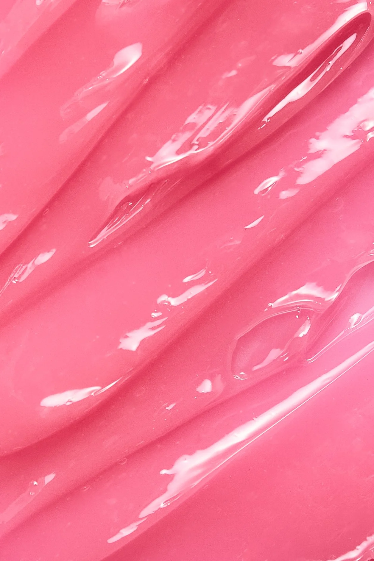 Close-up of pink and white striped candy or soap with glossy surface and flowing texture