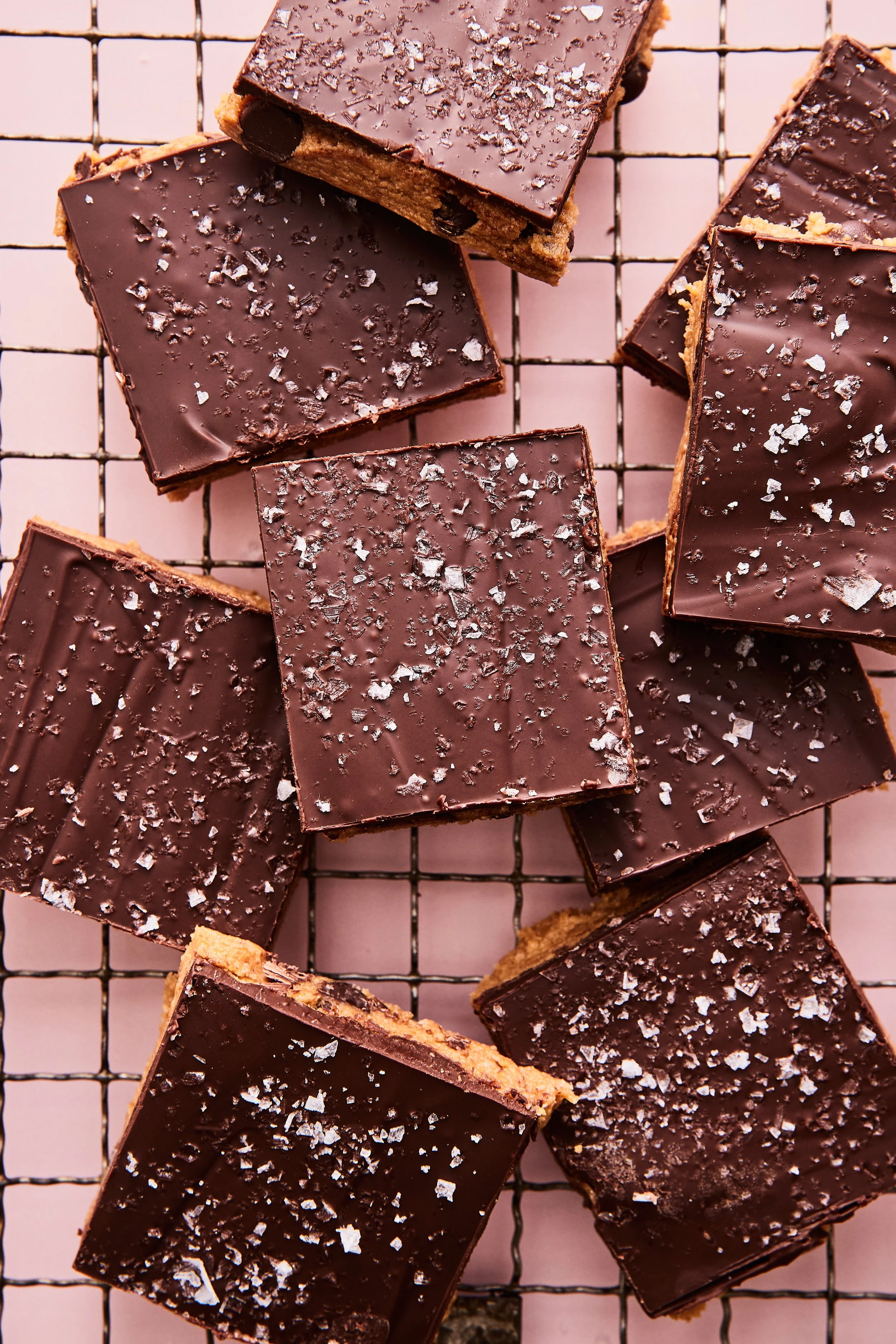 Squares of chocolate dessert with a sprinkle of sea salt on a wire cooling rack