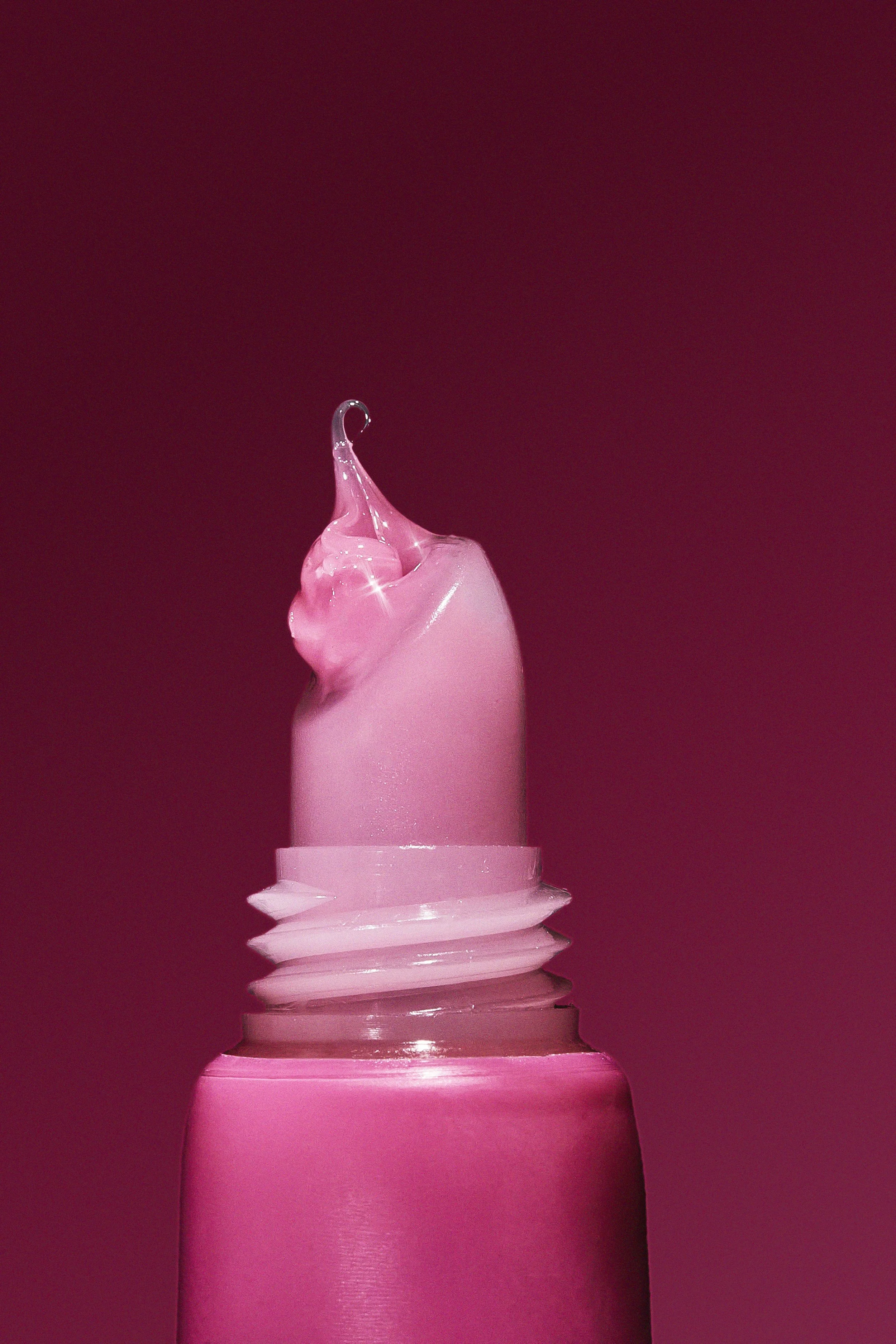 Close-up of a pink lipstick with the cap removed, showing the lipstick with a slight curl at the tip, against a matching pink background.