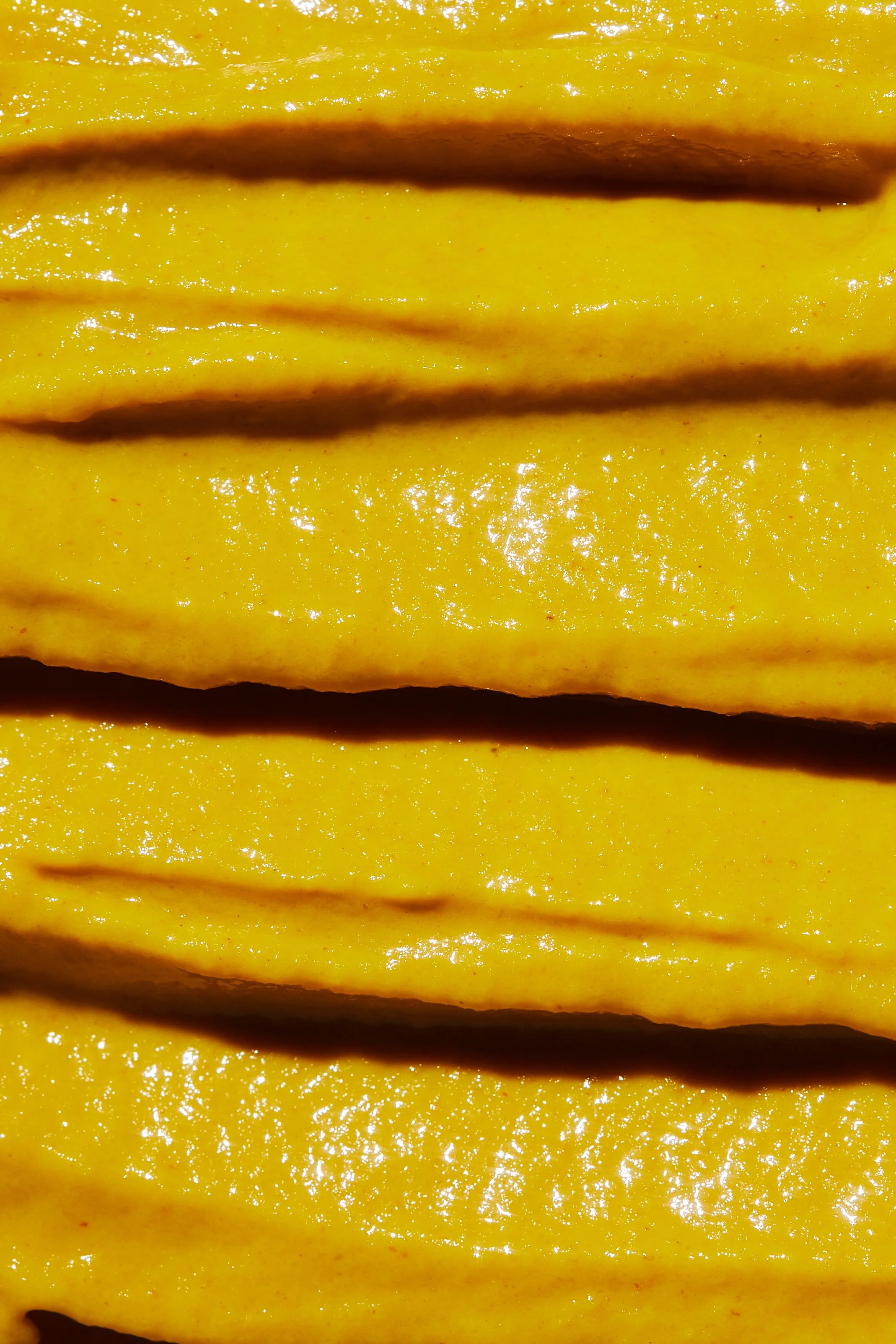 Close-up of sliced yellow mango with shiny, juicy flesh and dark brown seed lines.