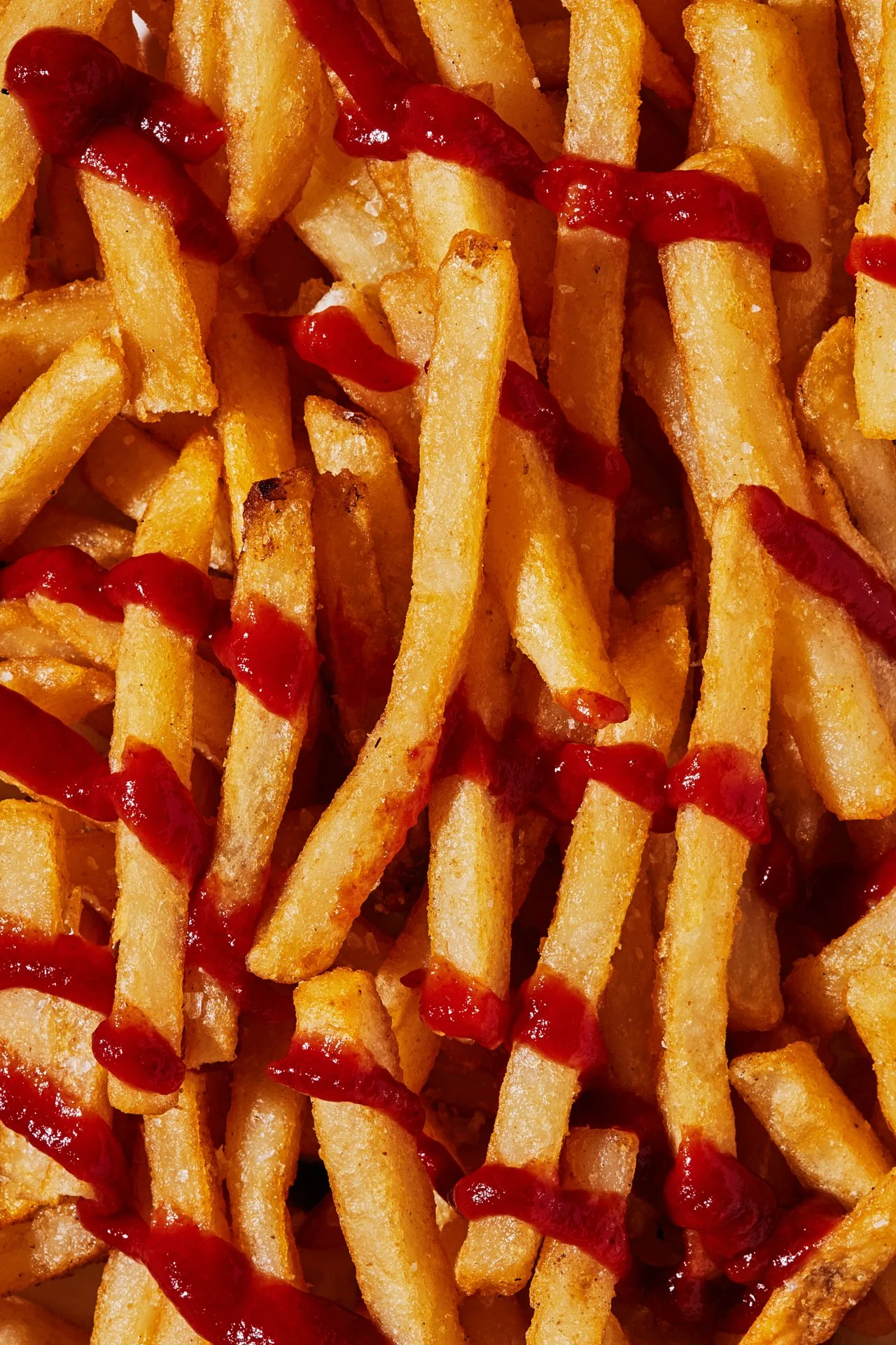 Close-up of French fries with ketchup drizzle.