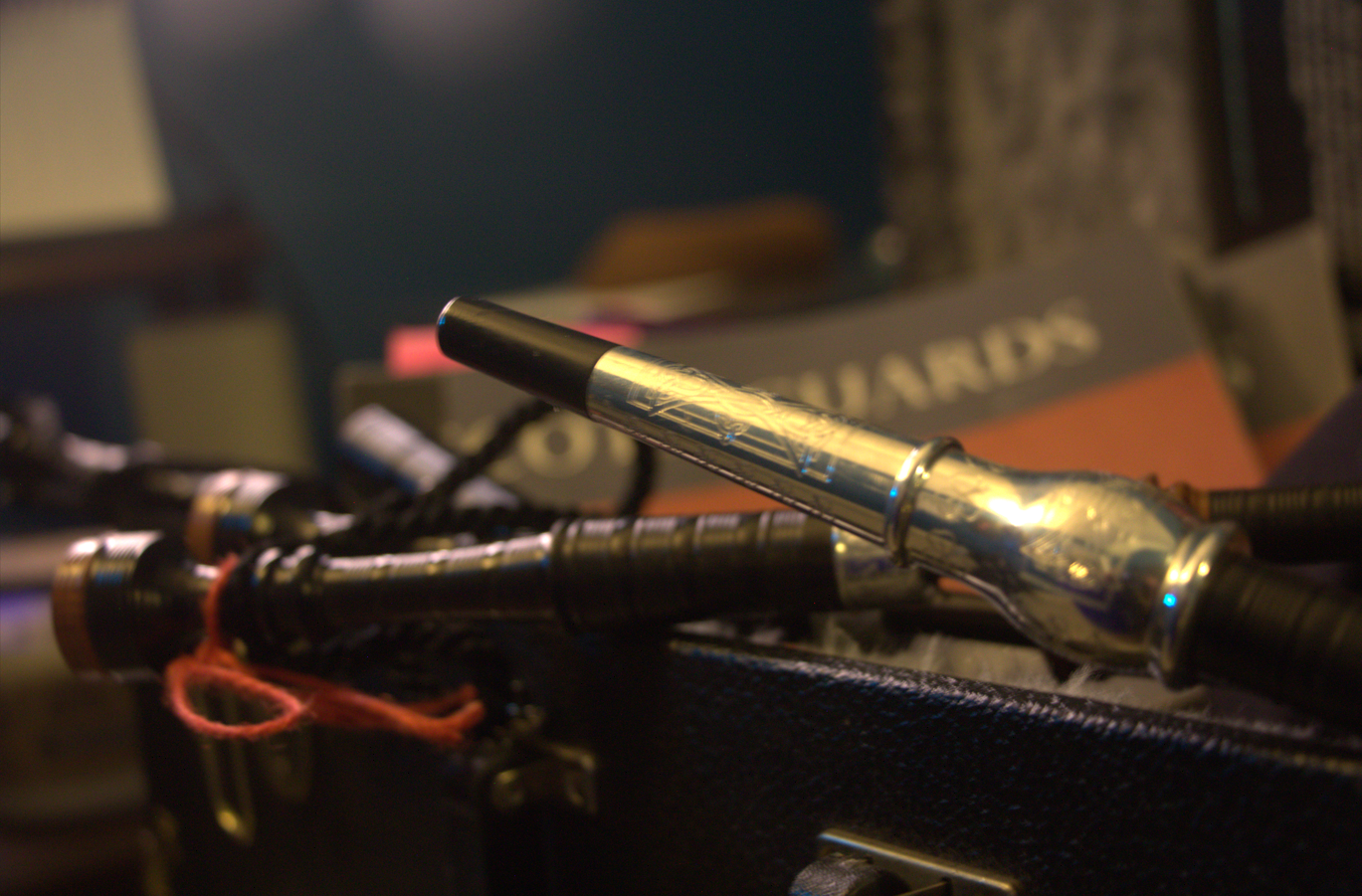 Close-up of a microphone resting on a guitar amplifier, with a blurred background that includes a board game box and assorted objects.
