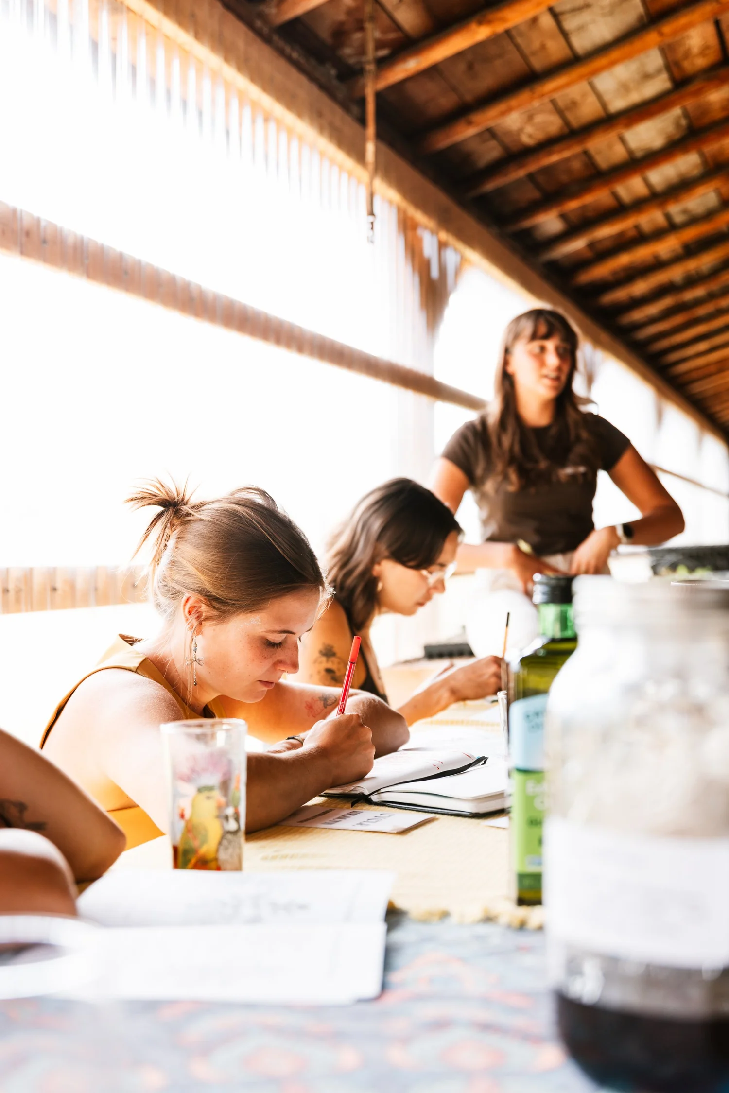Women writing and learning together at a long barn table workshop