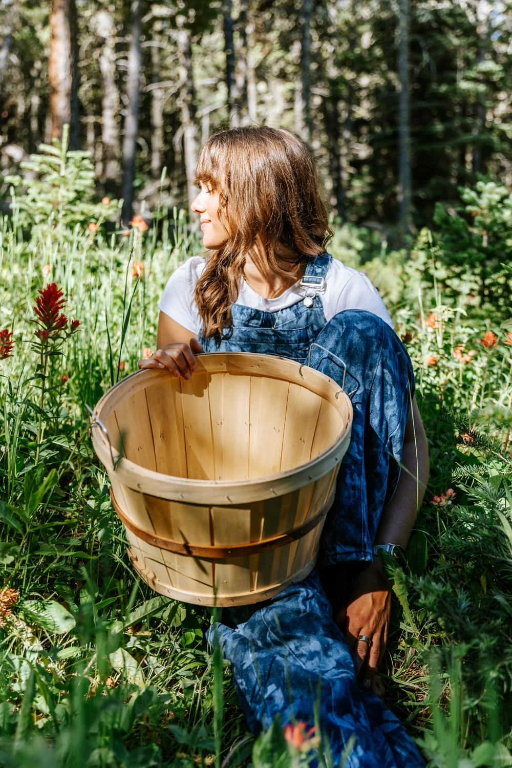Lauren sitting among wildflowers with a wooden harvest basket