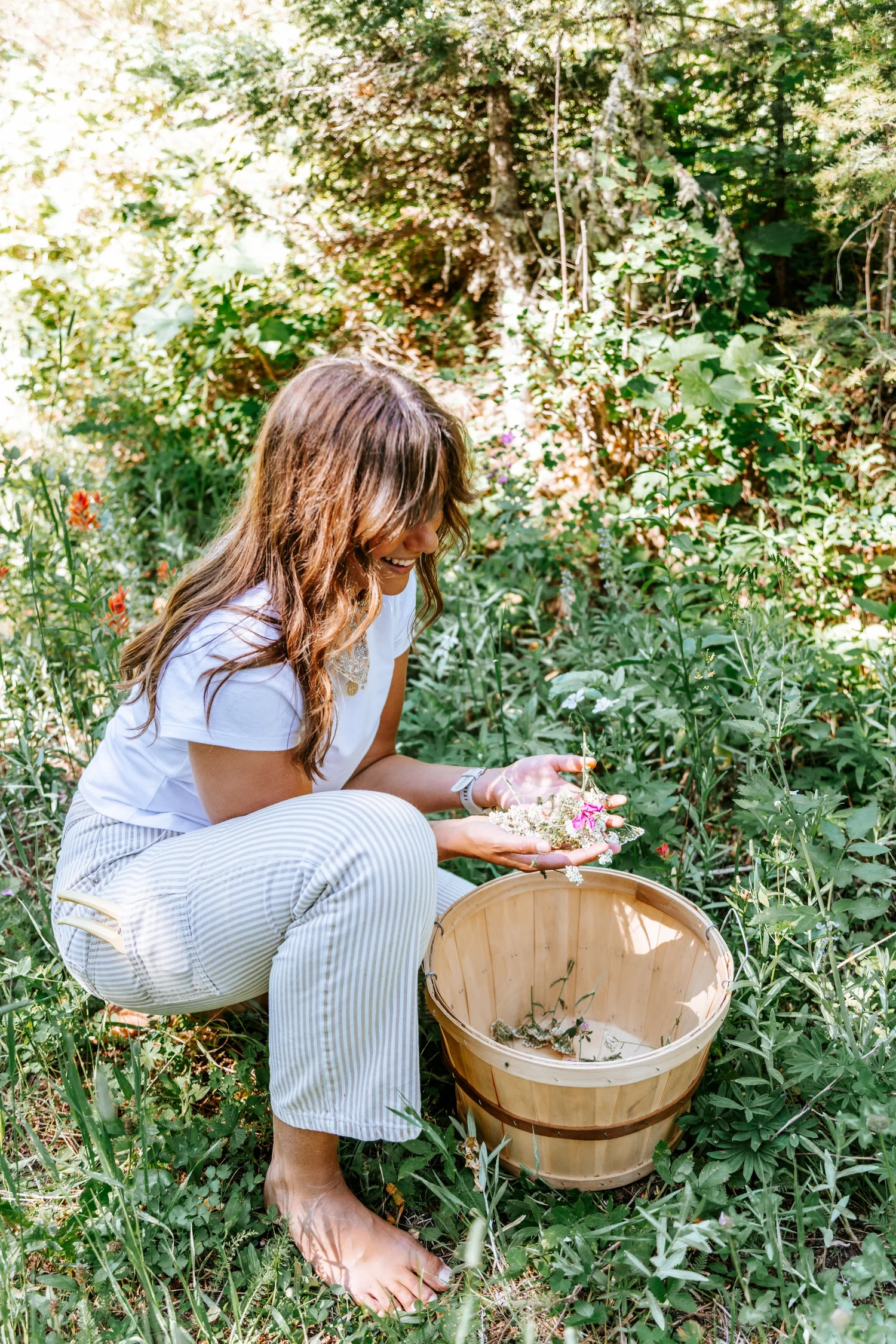 Lauren gathering flowers into a harvest basket in a garden