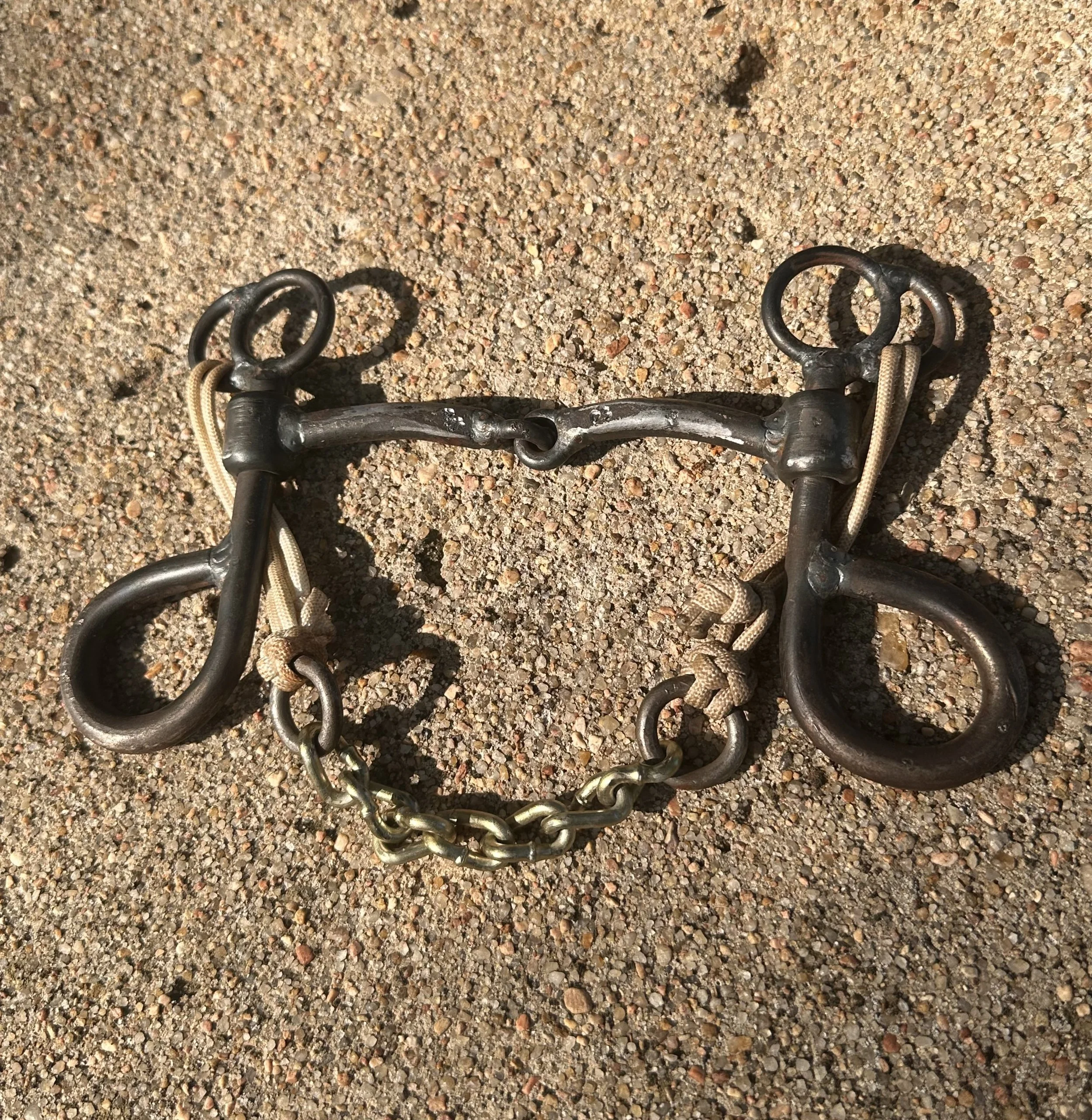 Shank runs down off of top headstall ring then loops back onto itself to form the reign ring- looks like a musical note with 1 full ring and a half ring welded toward the rider for the curb chain. Smooth sliding snaffle mouthpiece and curb chain