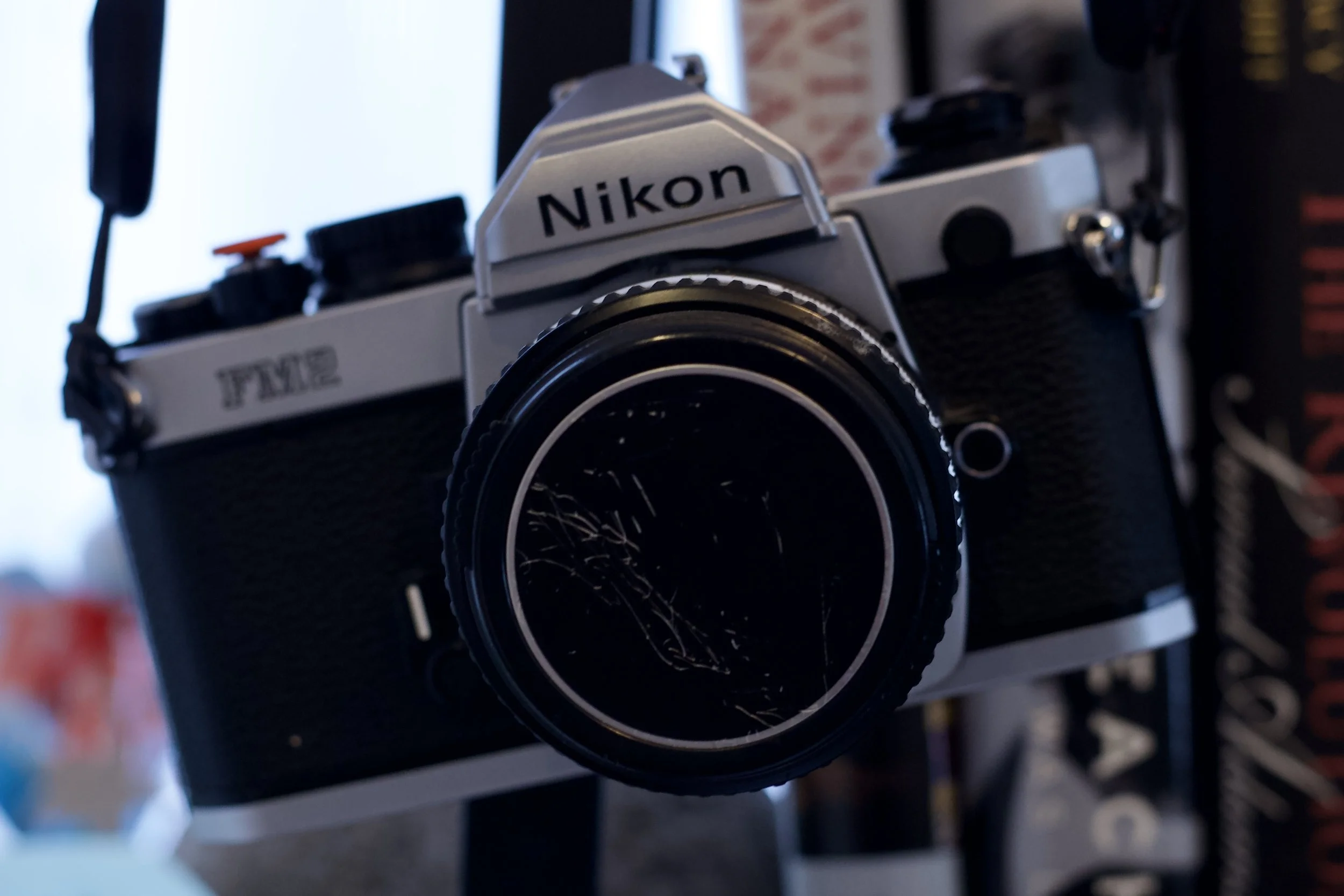 Close-up of a vintage Nikon FM2 film camera with lens cap, featuring silver and black design.
