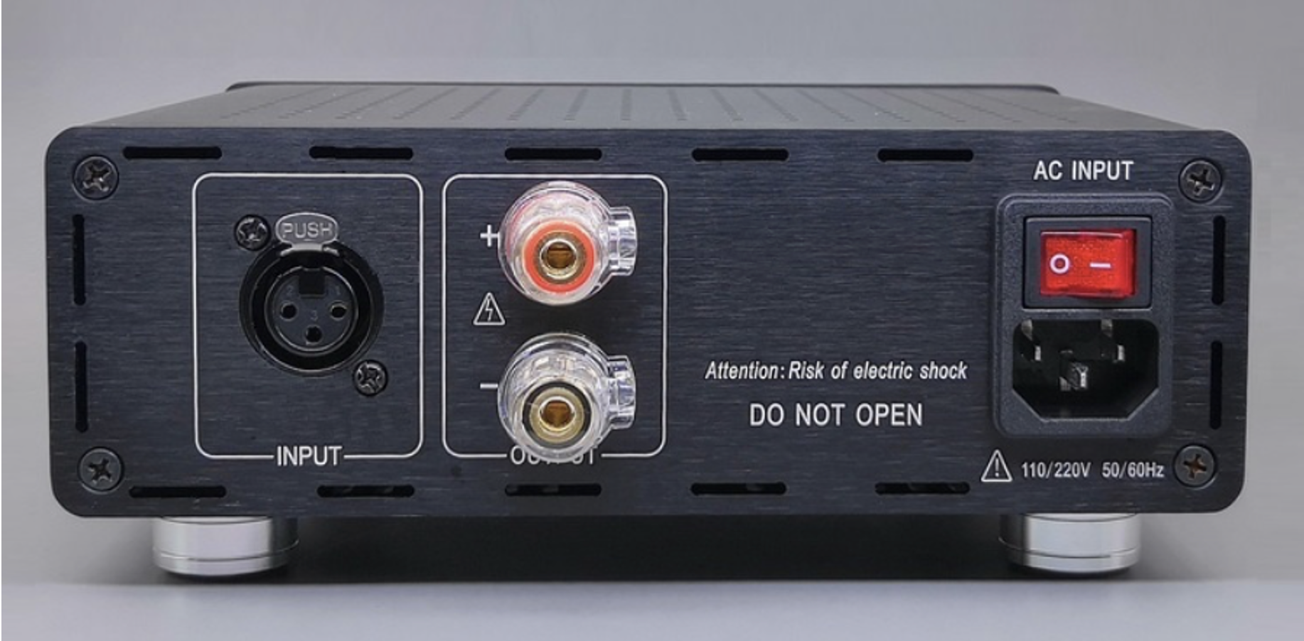 Panel trasero de un amplificador con entradas de audio, selector de voltaje, y botón de encendido con fuente de alimentación