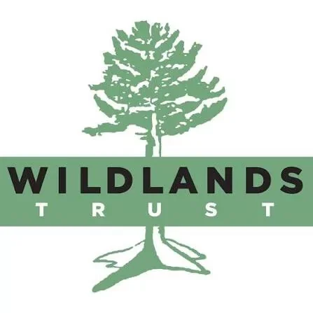 A logo featuring a green tree with the words "Wildlands Trust" in bold black and smaller white text underneath.