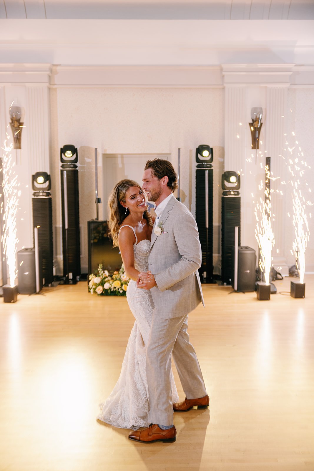 Bride and groom dancing at a wedding reception with sparklers and flowers