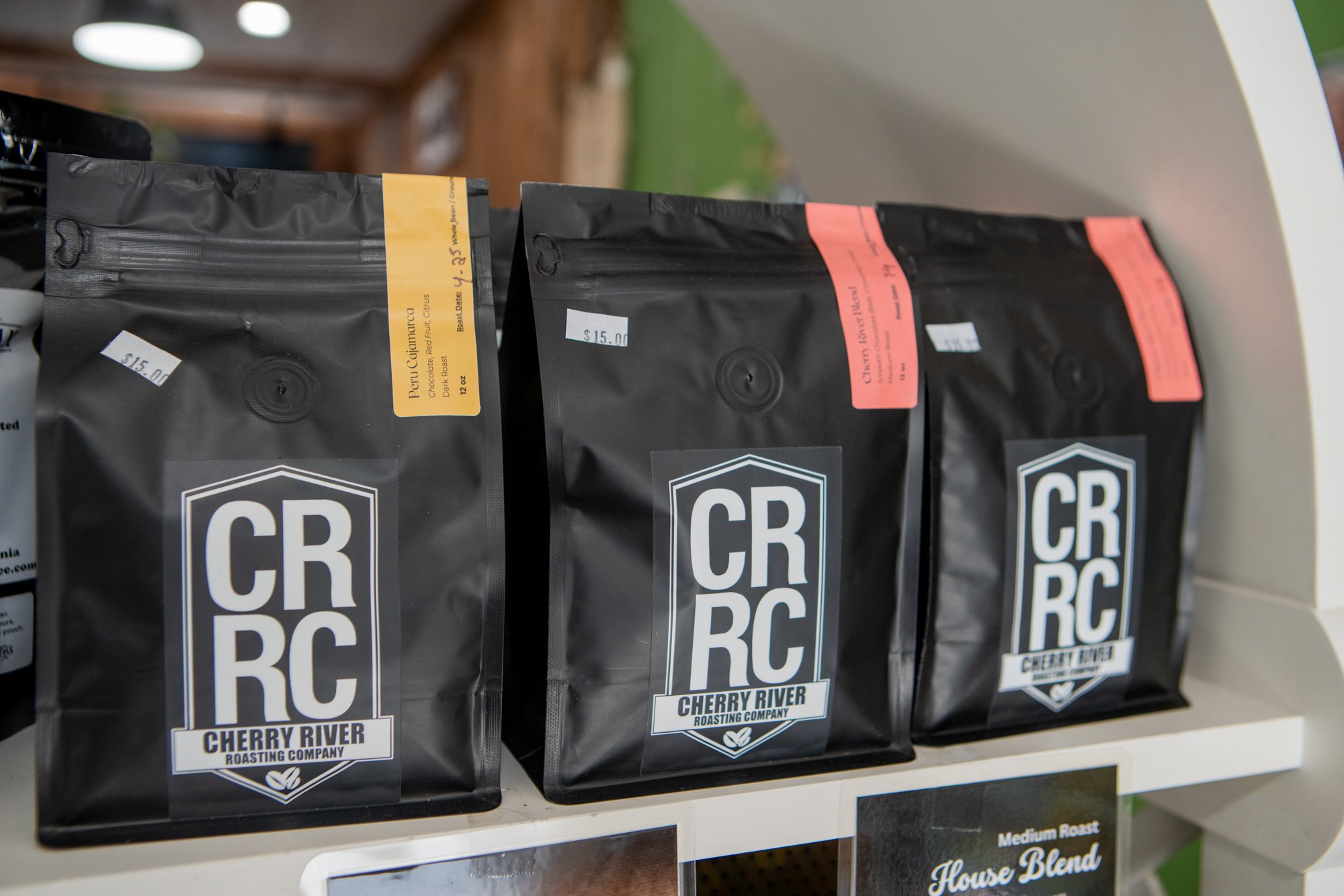 Bags of Cherry River Roasting Company coffee on a shelf, labeled with CR RC logos and individual blend labels.