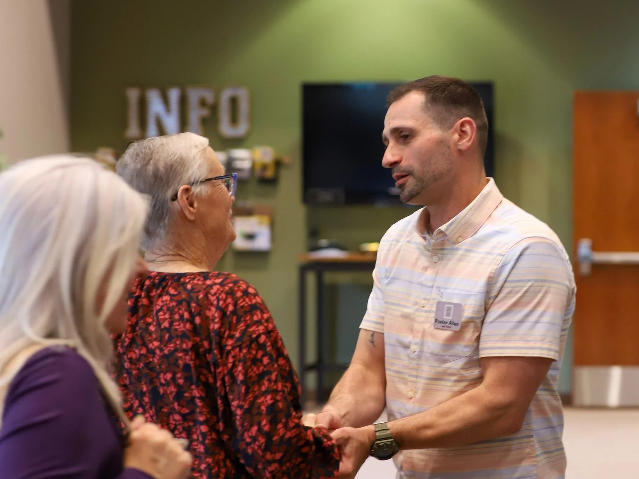 People gathering around a table with food at an outdoor event under a canopy.