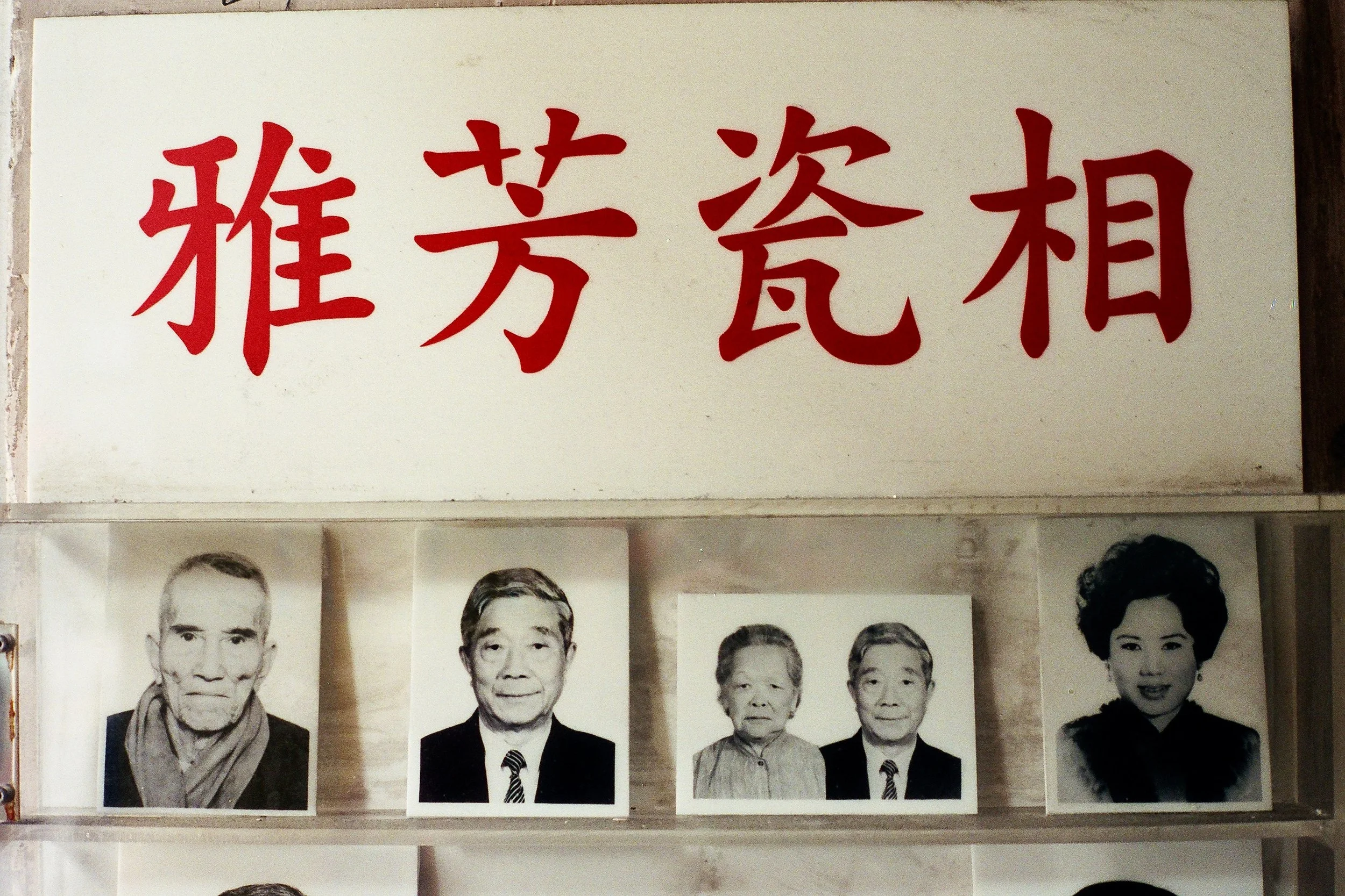 A sign with Chinese characters and black-and-white photographs of elderly people underneath.
