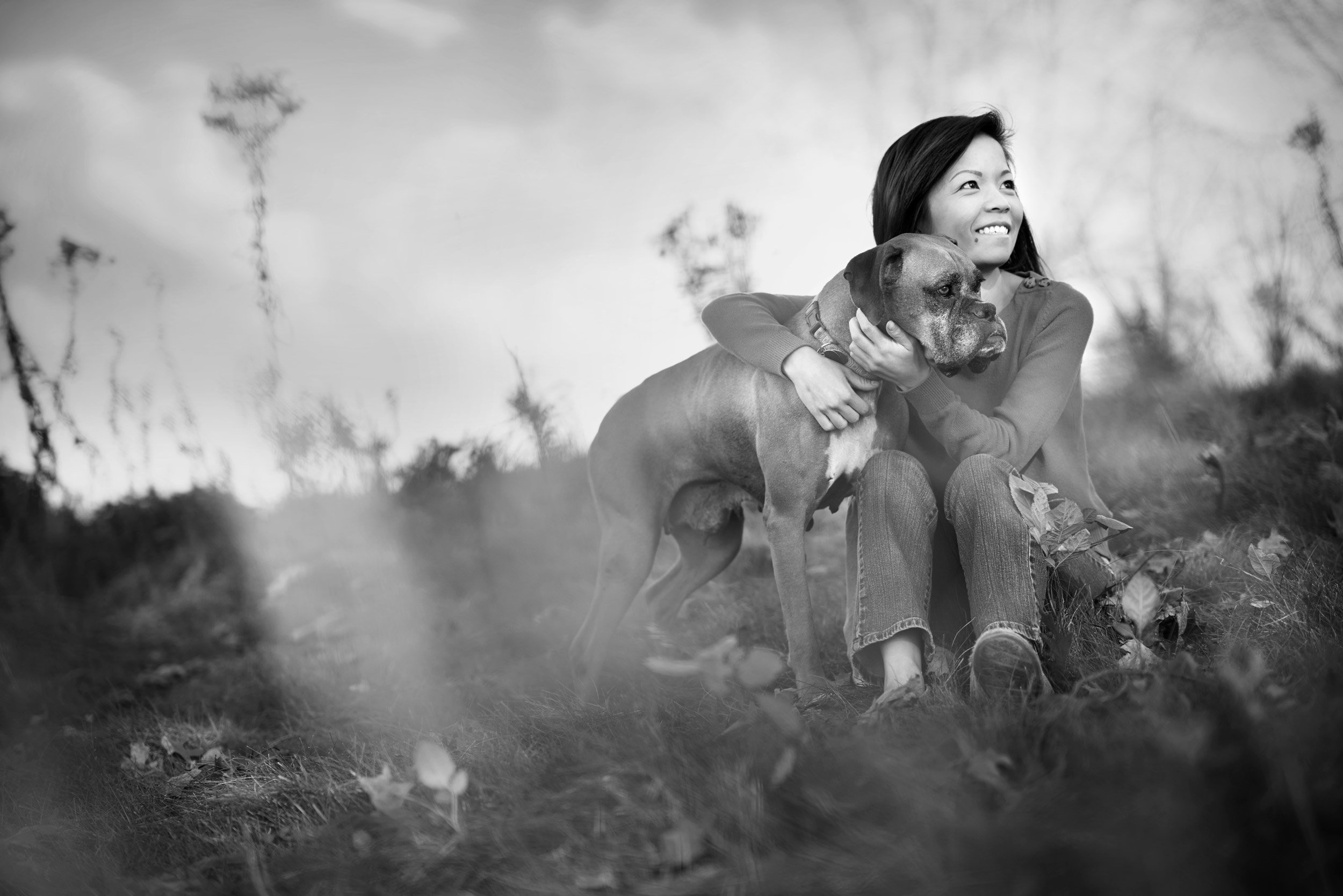 Photograph of a woman with her Boxer in a field of flowers