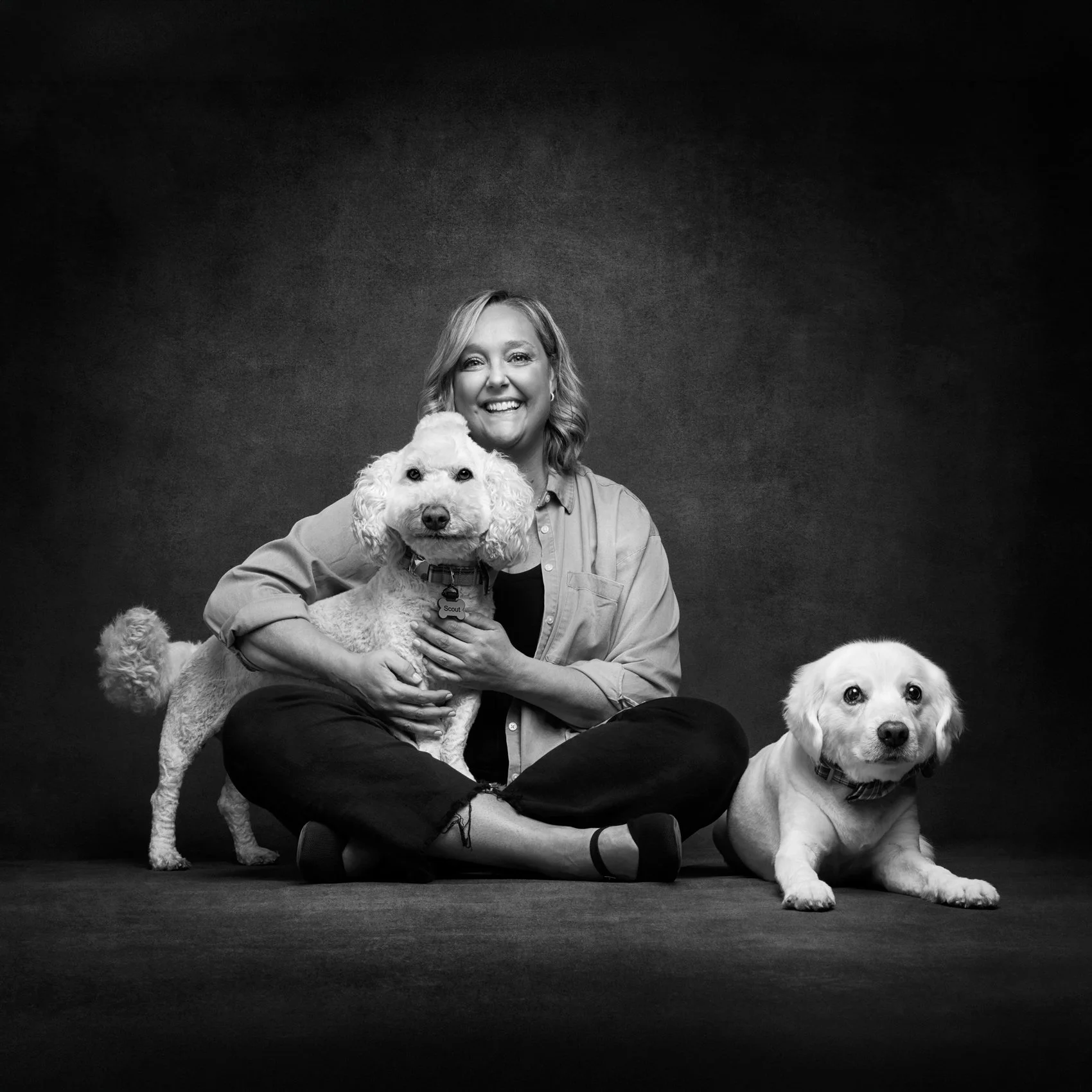 BW photo of a dog owner and her pups in studio.