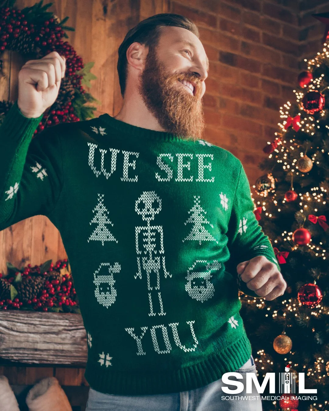 A man with a beard smiling and dancing in front of a decorated Christmas tree and holiday decor, wearing a green Christmas sweater that says 'We See You' with holiday-themed illustrations.