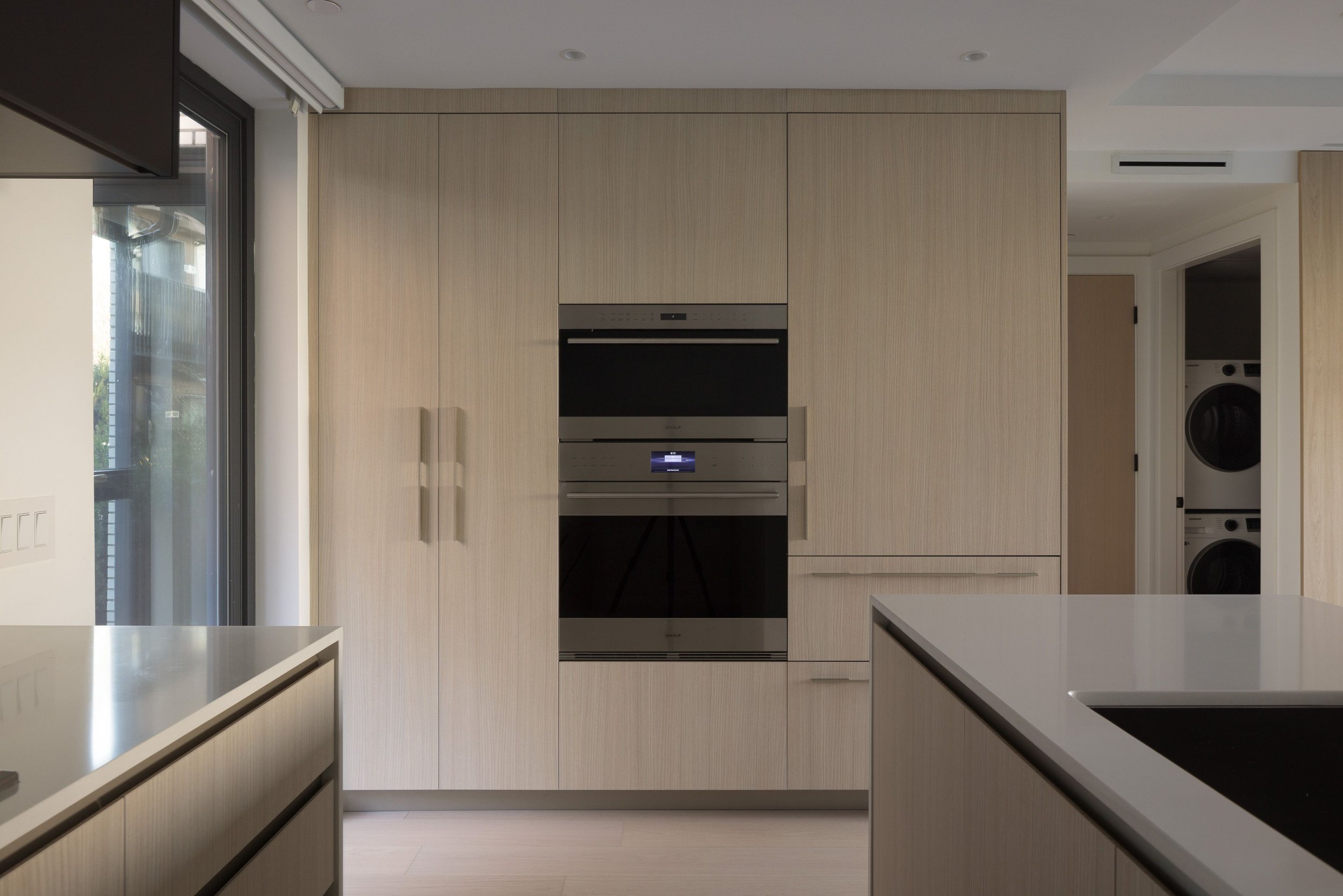 Modern kitchen with built-in appliances and light wood cabinetry